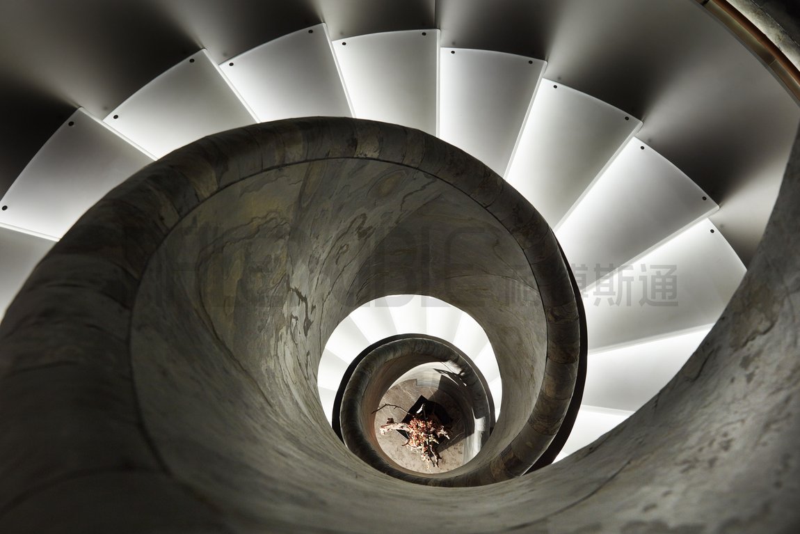 Flexible natural stone wrapping a spiral staircase with precise curved geometry